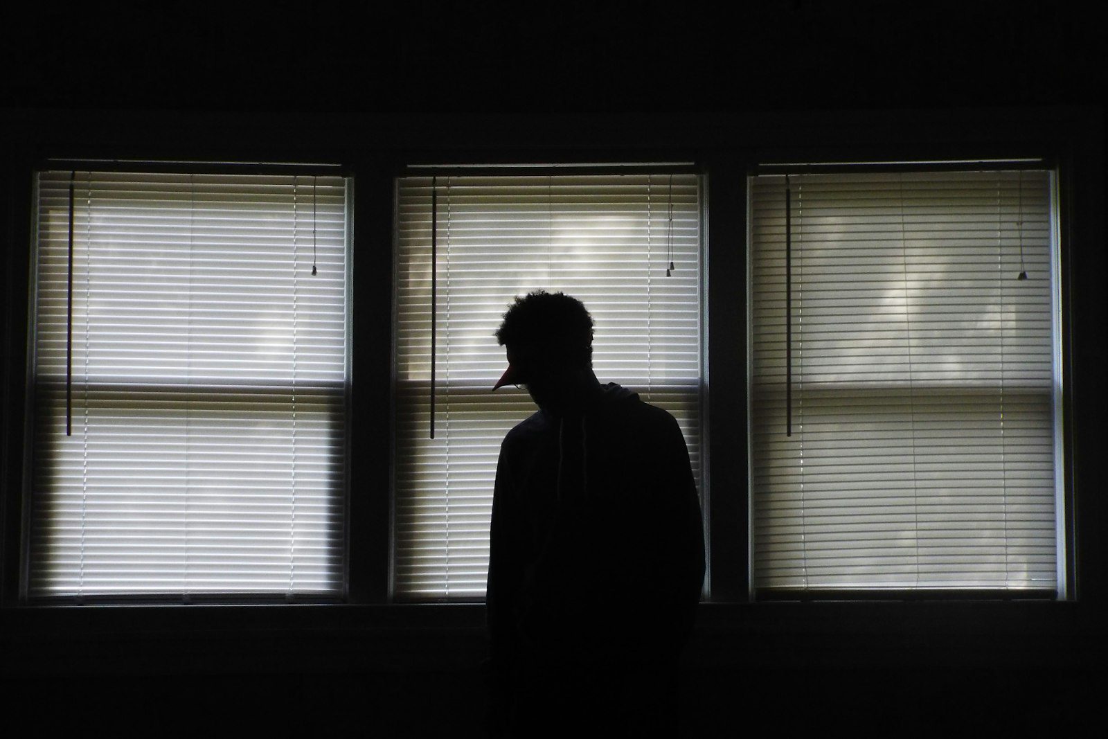 Silueta de una persona de pie frente a unas ventanas de noche